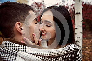 Girl with white teeth and black hair holds the guy`s face and st photo