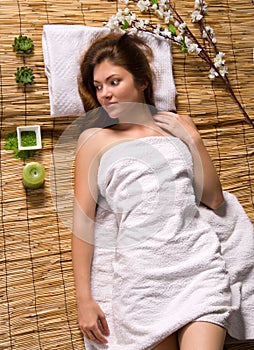 Girl in a white towel lying on spa treatments