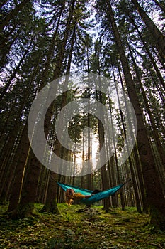 Girl who loves to travel relaxing in blue hammock into the Bavarian forest from Germany