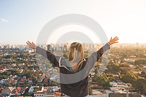 Girl with wide arms open at the top of a building photo