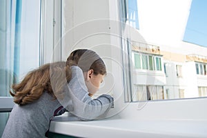 Girl on the windowsill, reaching into the open window