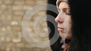 Girl in winter clothes chews the cud