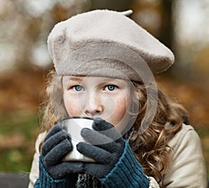 Girl in winter cloths drinking from flask cup