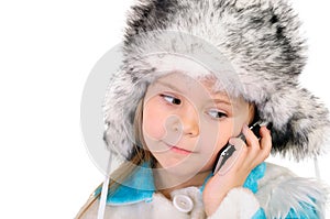 The girl in a winter fur cap speaks by phone