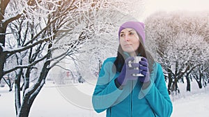 A girl in the winter in nature drinks hot tea from a thermos