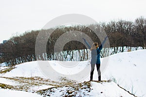 Girl in winter stands on a hill with his hands up. concept of freedom or victory