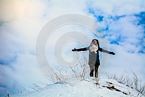 Girl in winter stands on a hill with his hands up. concept of freedom or victory