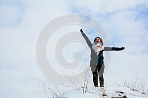 Girl in winter stands on a hill with his hands up. concept of freedom or victory