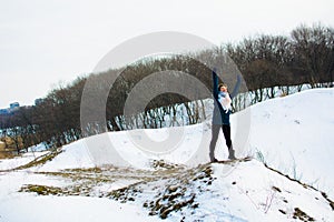 Girl in winter stands on a hill with his hands up. concept of freedom or victory