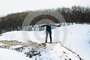 Girl in winter stands on a hill with his hands up. concept of freedom or victory
