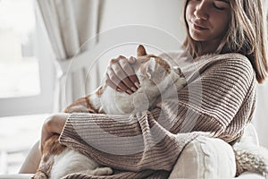 Girl in winter sweater sitting with cat on armchair photo