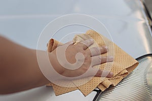 The girl wipes the window in the car with a yellow special cloth for windows.Close-up of a hand and a rag.there is a