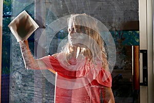 Girl wiping a dirty glass window