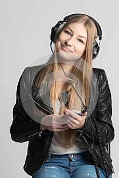 Girl in wired headphones is listening music from her phone