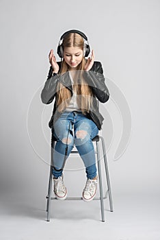 Girl in wired headphones is sitting and listening music