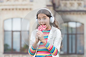 Girl wireless headphones eat lollipop candy, appetite concept