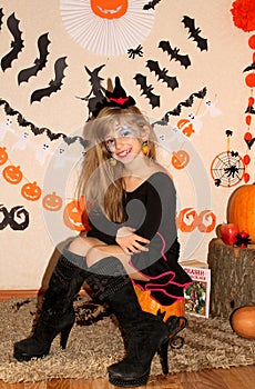 Girl in witch costume on Halloween on the pumpkin
