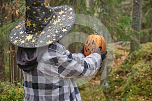 a girl in a witch costume holding pumpkin lantern, halloween concept, a girl plays with a jack lantern