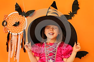 A girl in a witch costume holds a hat dreamily closing her eyes