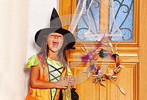 Girl in witch costume knock the door on Halloween
