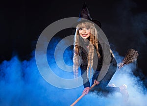 Girl in witch's hat flying on broomstick. photo