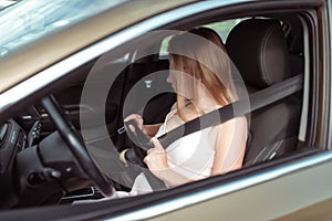 Girl woman in car summer city, fastens seat belt while sitting on seat, beginning of movement, concept of security, save