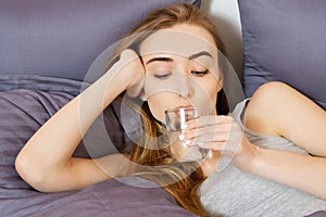 Girl woman drink water in bed at home, healthcare concept, hangover