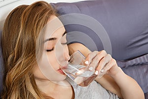 Girl woman drink water in bed at home, healthcare concept, hangover