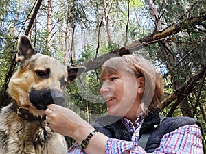 A girl or a woman and a German shepherd or Eastern European Shepherd dog in the forest, in nature, on a spring, summer