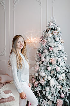 The girl, woman near Christmas tree. Happy New Year and Merry Christmas. Christmas decorated interior. The concept of family