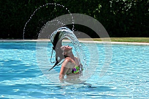 Girl or woman in swimming pool throwing wet hair back