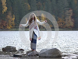 Girl on the wooden jetty at a lake in autumn season
