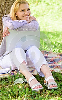 Girl work with laptop in park sit on grass. Natural environment office. Woman with laptop work outdoors lean tree