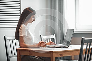 Girl working on computer laptop in light room