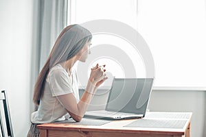 Girl working on computer laptop in light room