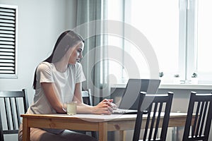 Girl working on computer laptop in light room