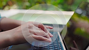 girl working on a computer in a tropical climate. typing on laptop