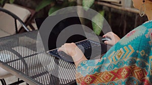 girl working on a computer in a tropical climate. typing on laptop