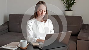 Girl working at home and typing in a laptop.