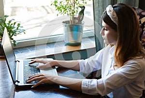 The girl works at the computer in a cafe