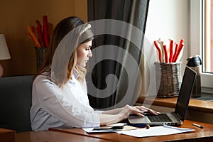 The girl works at the computer in a cafe