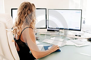 The girl works at the computer in the office. Business, business woman, workplace. Space for text, rear view