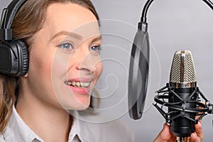 A girl works with a microphone, recordings Audio recording on the radio, or dubbing an audiobook, news on the radio, or blogging