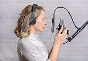 A girl works with a microphone, recordings Audio recording on the radio, or dubbing an audiobook, news on the radio, or blogging