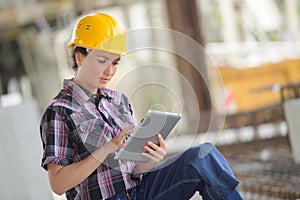 girl in workwear safety helmet using tablet touchpad