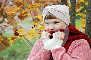 Girl wrap oneself in red scarf to warm in autumn outdoors