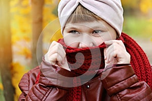Girl wrapped in red scarf so that it was warm in autumn outdoors, close-up face