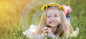 A girl in a wreath of dandelions lying on the grass. Spring concept