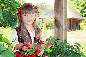 Girl in a wreath and a suit with the Ukrainian ornament in the countryside with wooden houses