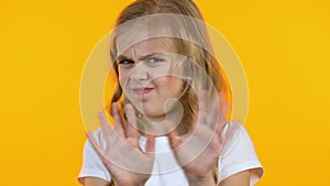Girl wrinkling nose and rejecting from unhealthy sweets, yellow background